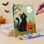 Painting a Little Autumn Witches mini canvas propped up beside numbered acrylic paints