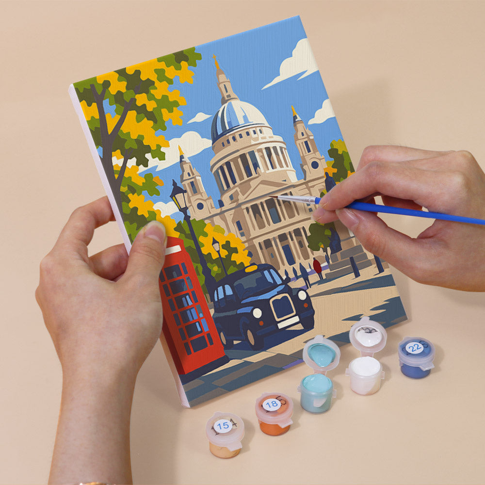 Hand holding a London Days mini canvas while painting the details