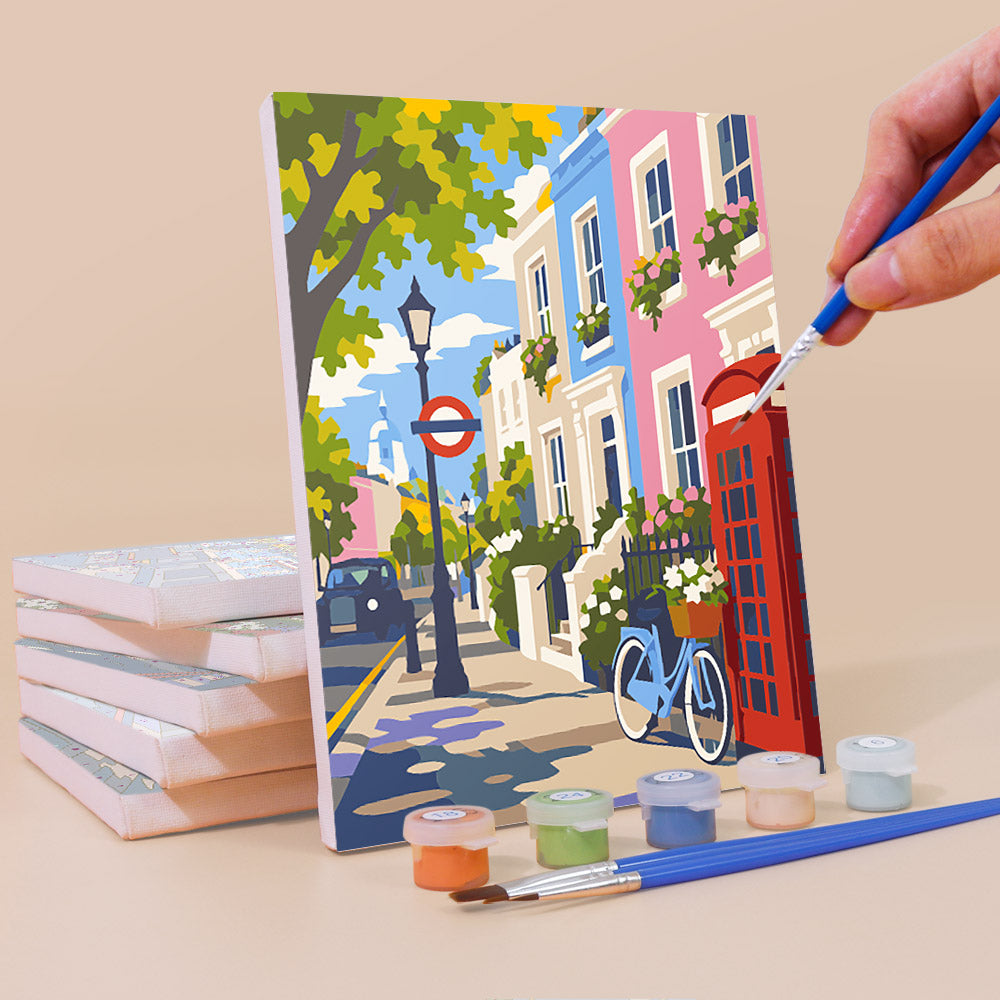 Painting a London Days mini canvas propped up beside numbered acrylic paints