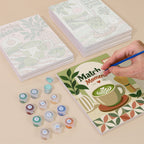 Painting one of the Matcha Moments designs next to a stack of mini canvases