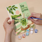 Hand holding a Matcha Moments mini canvas while painting the details