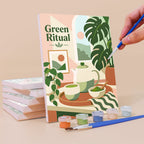 Painting a Matcha Moments mini canvas propped up beside numbered acrylic paints