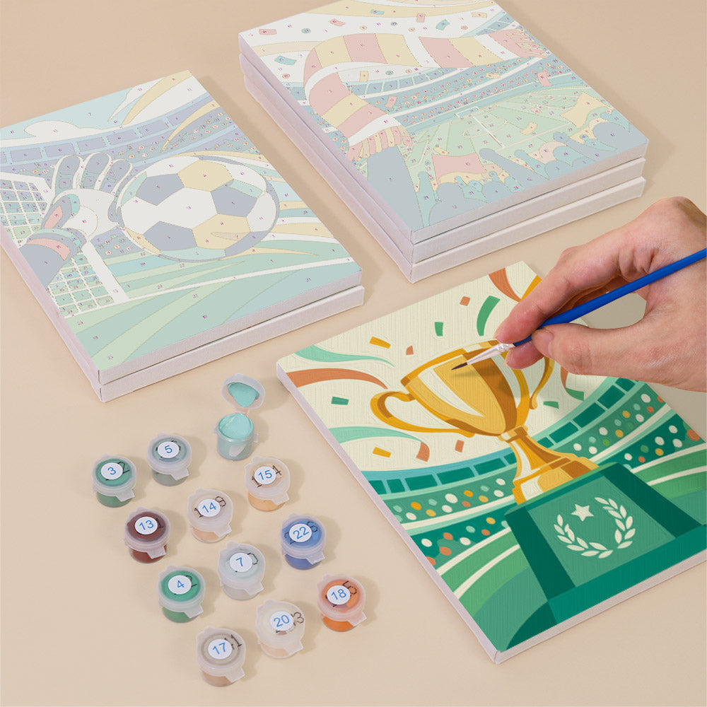 Painting one of the Matchday Magic designs next to a stack of mini canvases