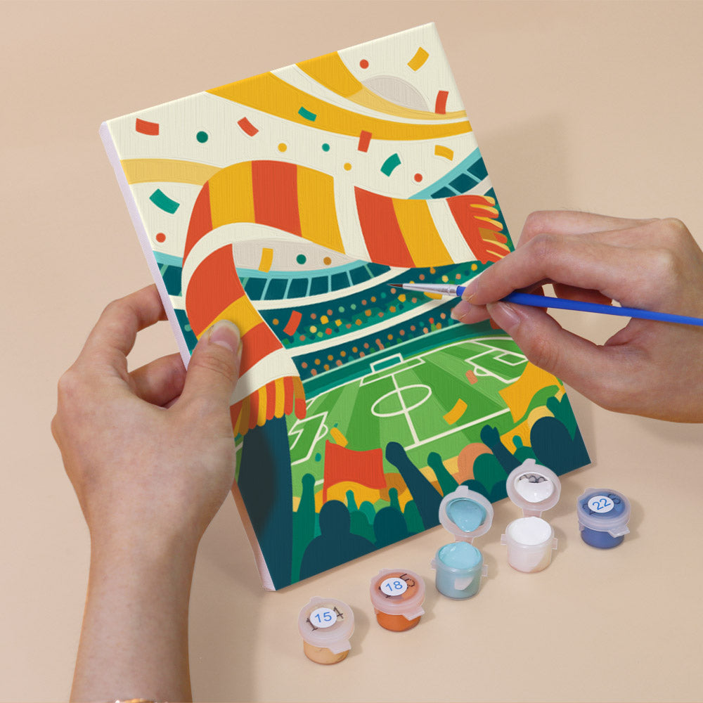Hand holding a Matchday Magic mini canvas while painting the details