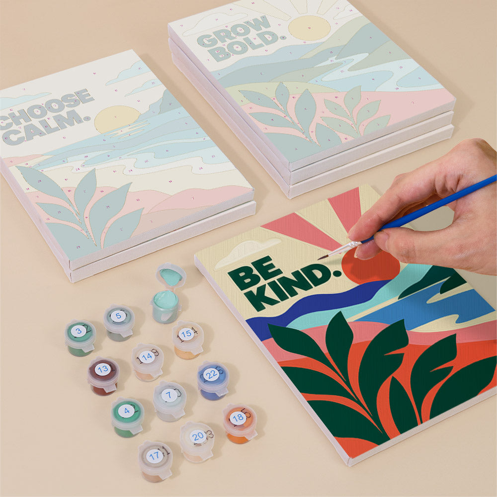 Painting one of the Mindful Mantras designs next to a stack of mini canvases