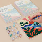 Painting one of the Mindful Mantras designs next to a stack of mini canvases