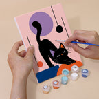 Hand holding a Mod Cats mini canvas while painting the details