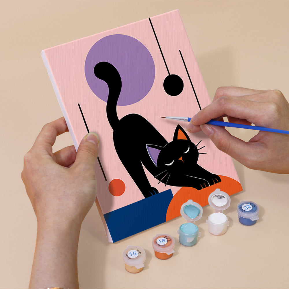 Hand holding a Mod Cats mini canvas while painting the details