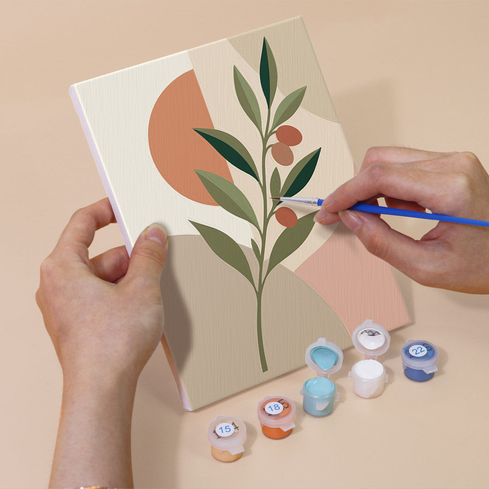 Hand holding a Modern Leaves mini canvas while painting the details