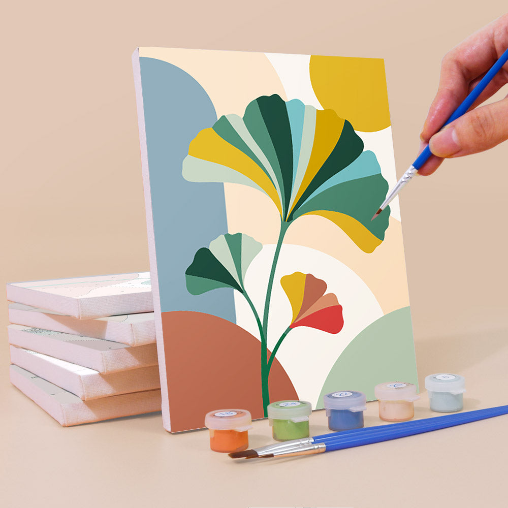 Painting a Modern Leaves mini canvas propped up beside numbered acrylic paints