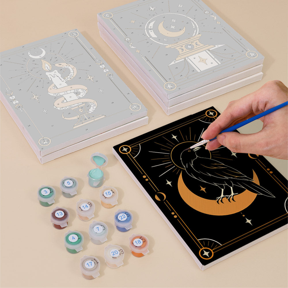 Painting one of the Moon Magic designs next to a stack of mini canvases