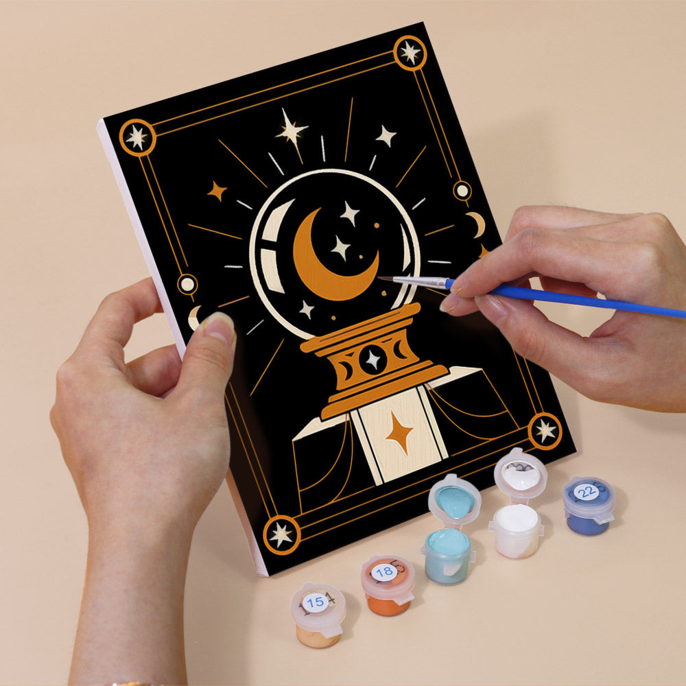 Hand holding a Moon Magic mini canvas while painting the details