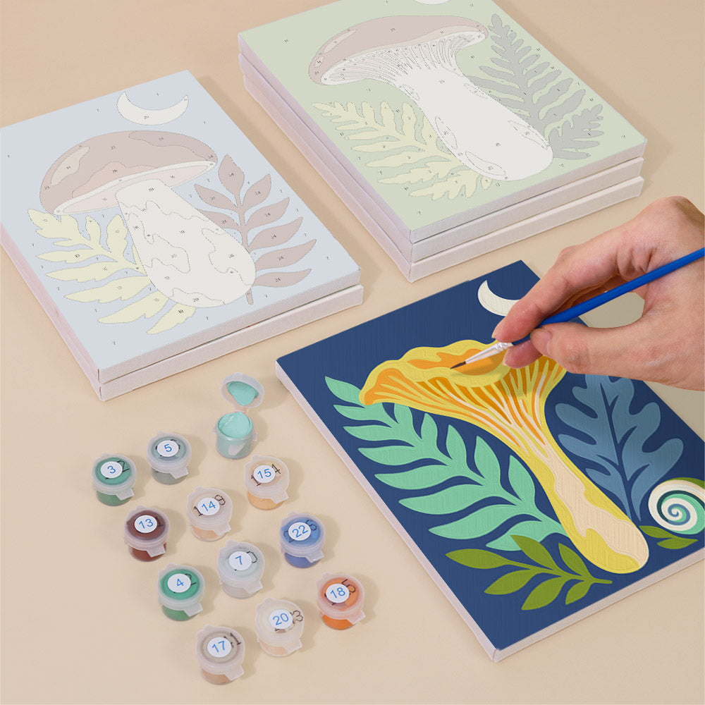 Painting one of the Moon Mushrooms designs next to a stack of mini canvases