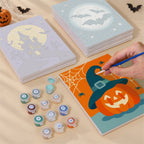Painting one of the Moonlit Halloween designs next to a stack of mini canvases