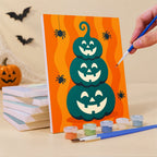 Painting a Moonlit Halloween mini canvas propped up beside numbered acrylic paints