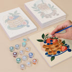 Painting one of the Morning Treats designs next to a stack of mini canvases
