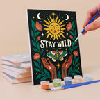 Painting a Mystic Folk mini canvas propped up beside numbered acrylic paints