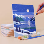 Painting a Night Sky Journeys mini canvas propped up beside numbered acrylic paints