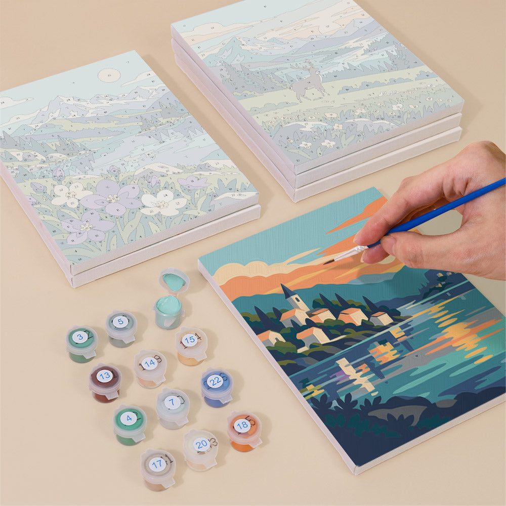 Painting one of the Northern Wilds designs next to a stack of mini canvases