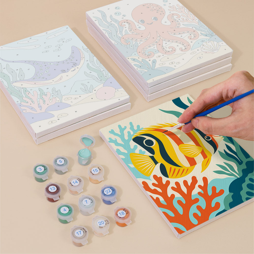 Painting one of the Ocean Friends designs next to a stack of mini canvases