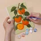 Hand holding an Orchard Harvest mini canvas while painting the details