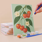 Painting an Orchard Harvest mini canvas propped up beside numbered acrylic paints