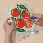 Hand holding a Pantry Harvest mini canvas while painting the details