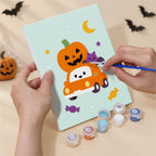 Hand holding a Pastel Pumpkin Pals mini canvas while painting the details