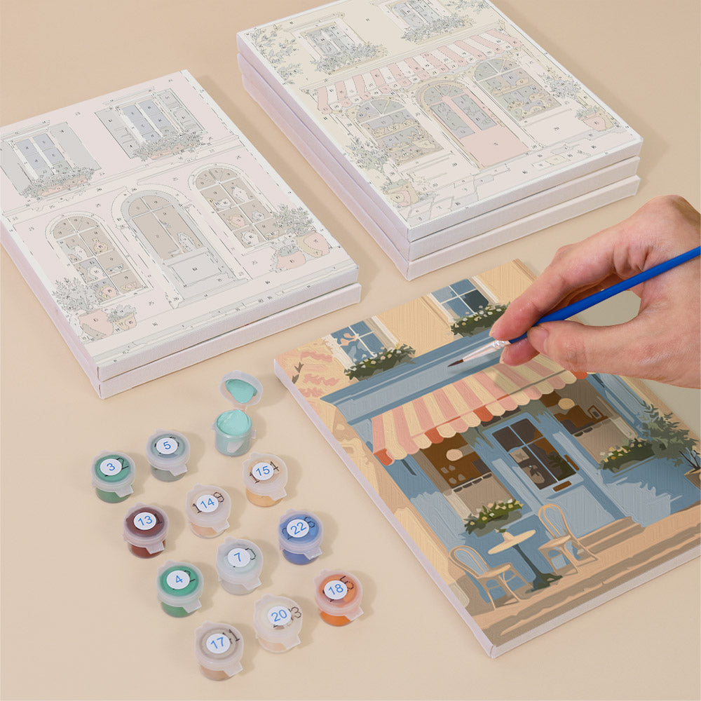 Painting one of the Pastel Storefronts designs next to a stack of mini canvases