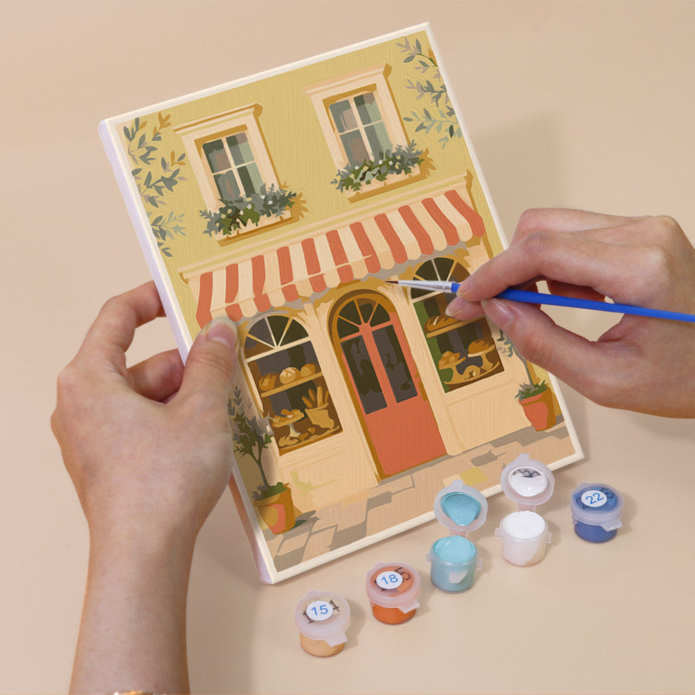 Hand holding a Pastel Storefronts mini canvas while painting the details