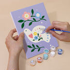 Hand holding a Peace Doves mini canvas while painting the details