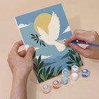 Hand holding a Peaceful Faith mini canvas while painting the details