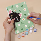 Hand holding a Peekaboo Kittens mini canvas while painting the details
