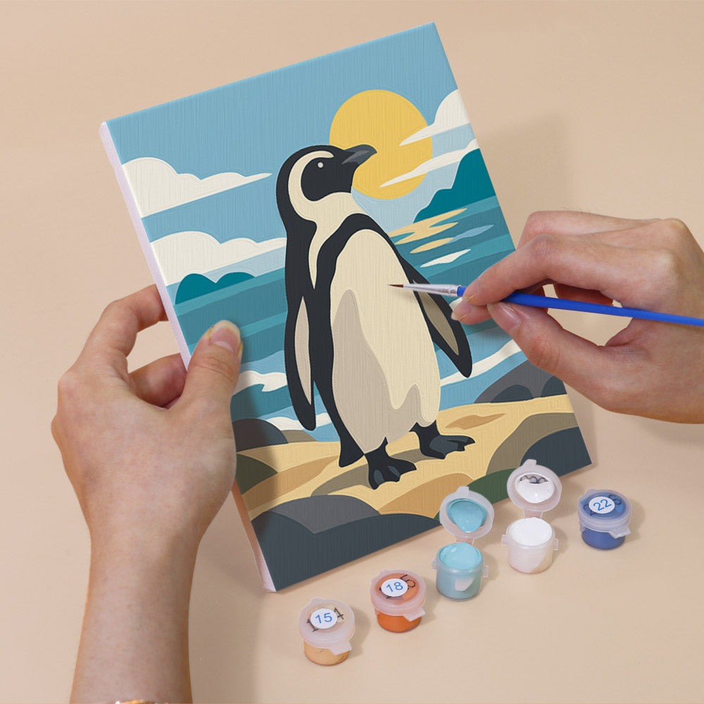 Hand holding a Penguin Shores mini canvas while painting the details