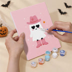 Hand holding a Pink Boo Crew mini canvas while painting the details