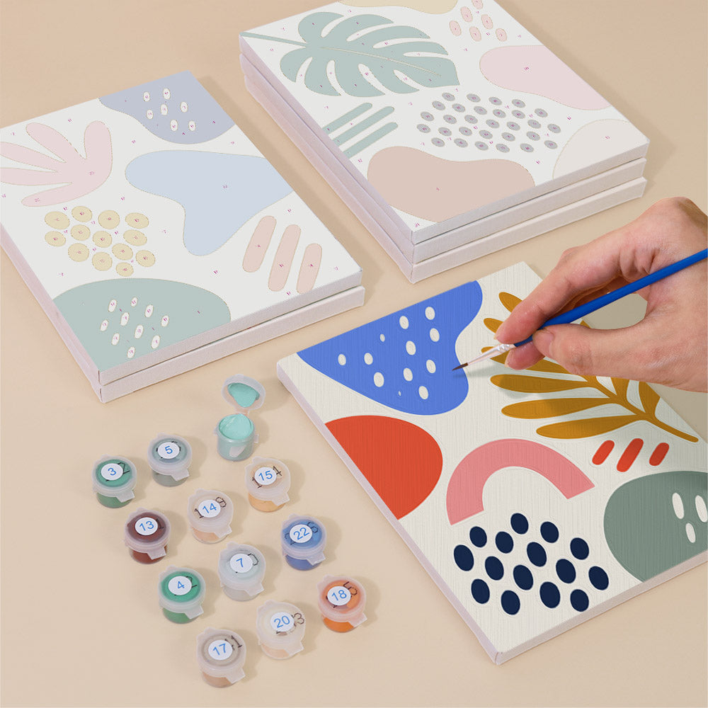 Painting one of the Playful Shapes designs next to a stack of mini canvases