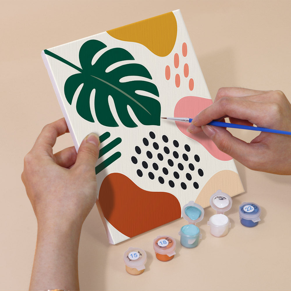 Hand holding a Playful Shapes mini canvas while painting the details