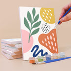Painting a Playful Shapes mini canvas propped up beside numbered acrylic paints