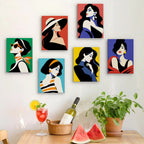 Six finished Pop Art Ladies mini paintings hung on a wall above a table