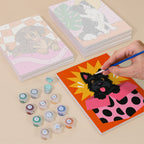 Painting one of the Pop Pups designs next to a stack of mini canvases