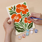 Hand holding a Poppy Parade mini canvas while painting the details