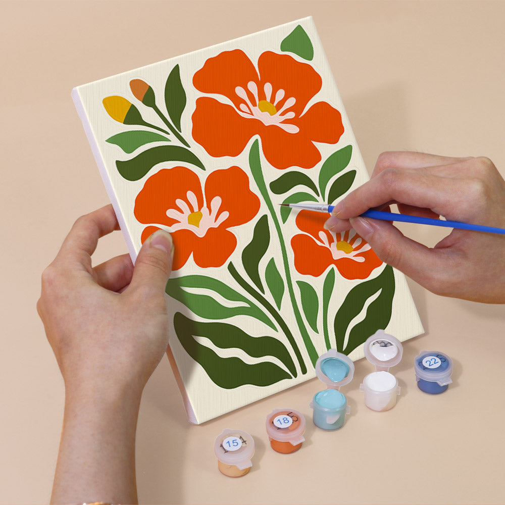 Hand holding a Poppy Parade mini canvas while painting the details
