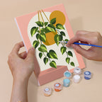 Hand holding a Potted Greens mini canvas while painting the details