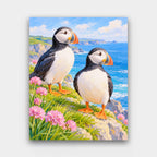 Puffins on the Cliff paint by numbers kit of two puffins on a grassy sea cliff with pink sea thrift and blue sea
