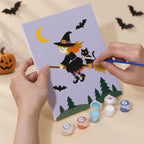 Hand holding a Pumpkin Festivities mini canvas while painting the details