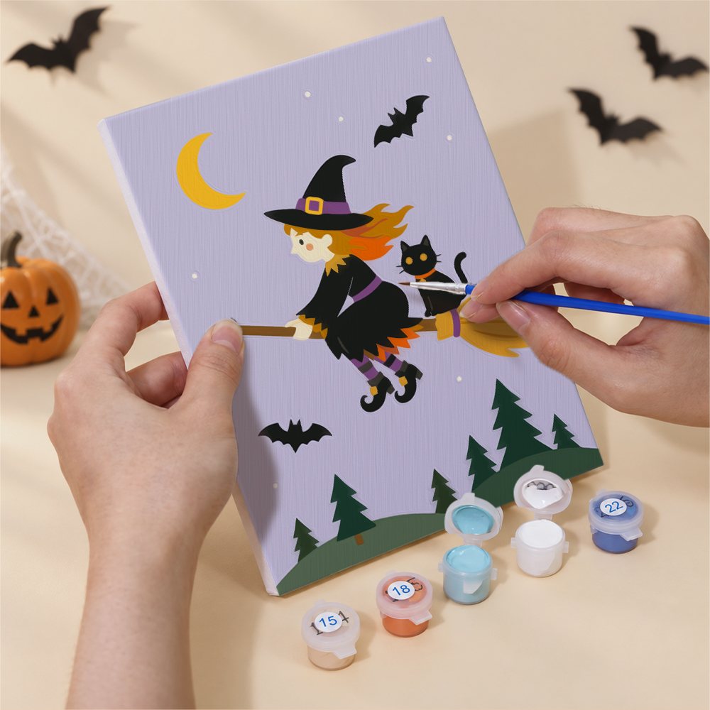 Hand holding a Pumpkin Festivities mini canvas while painting the details