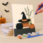 Painting a Quiet Hauntings mini canvas propped up beside numbered acrylic paints
