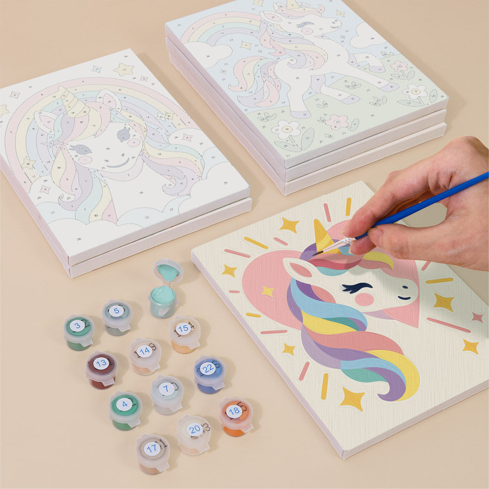 Painting one of the Rainbow Unicorns designs next to a stack of mini canvases
