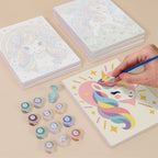 Painting one of the Rainbow Unicorns designs next to a stack of mini canvases