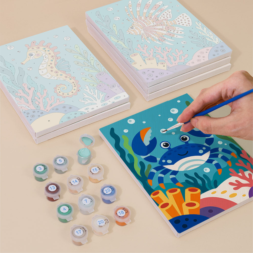 Painting one of the Reef Friends designs next to a stack of mini canvases
